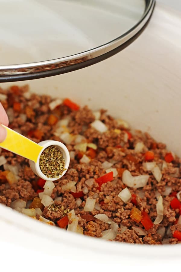 Adding Italian seasoning to the beef and vegetables in the crockpot