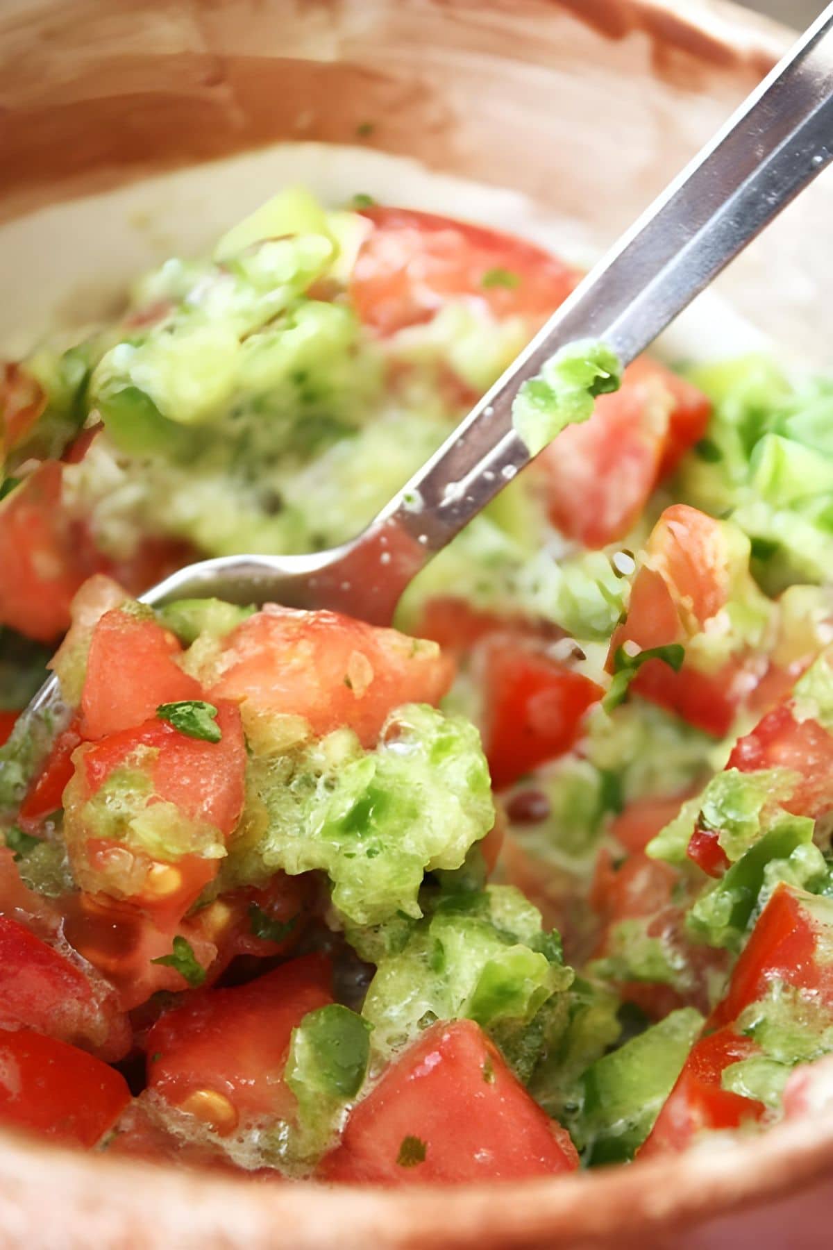A spoon mixing up fresh salsa.