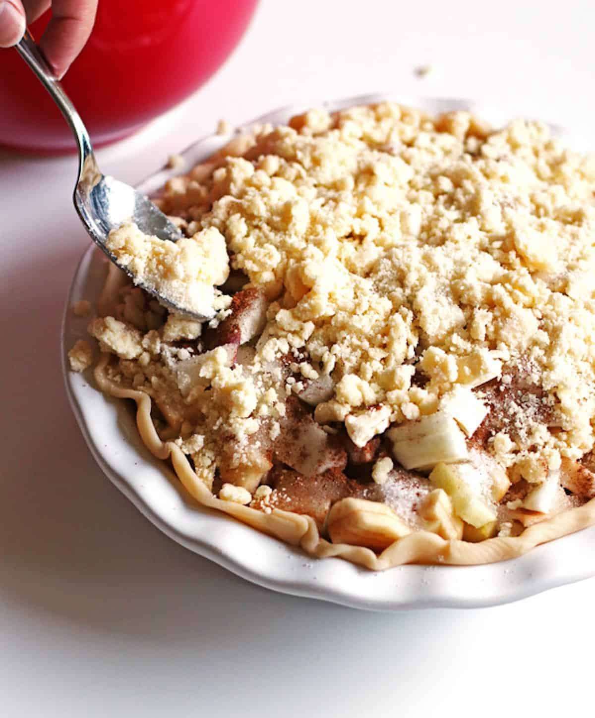 Adding crumb topping to top of the pie using a spoon