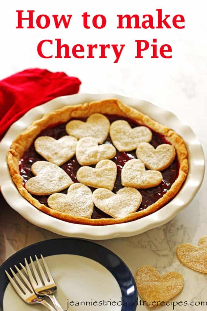 Cherry Pie in a white pie dish with cut out hearts on top sprinkled with powdered sugar