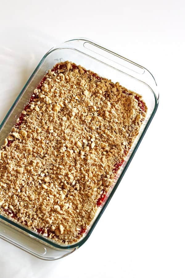 Crumb mixture on top of strawberry rhubarb bars in baking dish