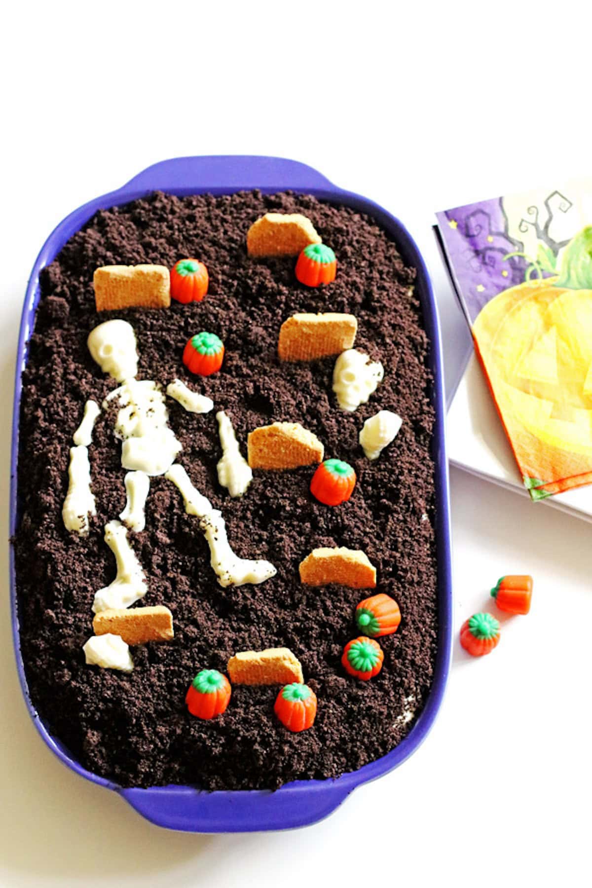 Dirt Cake decorated as a graveyard with candy pumpkins, candy skeleton and cookies as tombstones