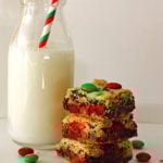 M&M Cookie Bars stacked with a glass of milk next to them
