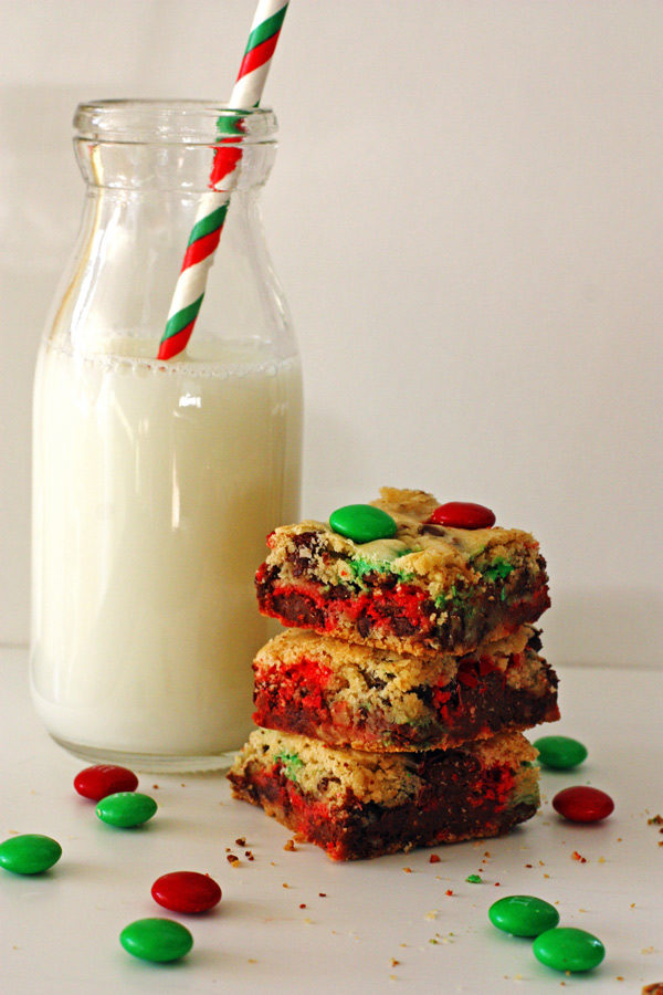 M&M Cookie Bars stacked with a glass of milk next to them