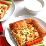 Slice of Buffalo Chicken Pizza on a white plate with carrots and celery