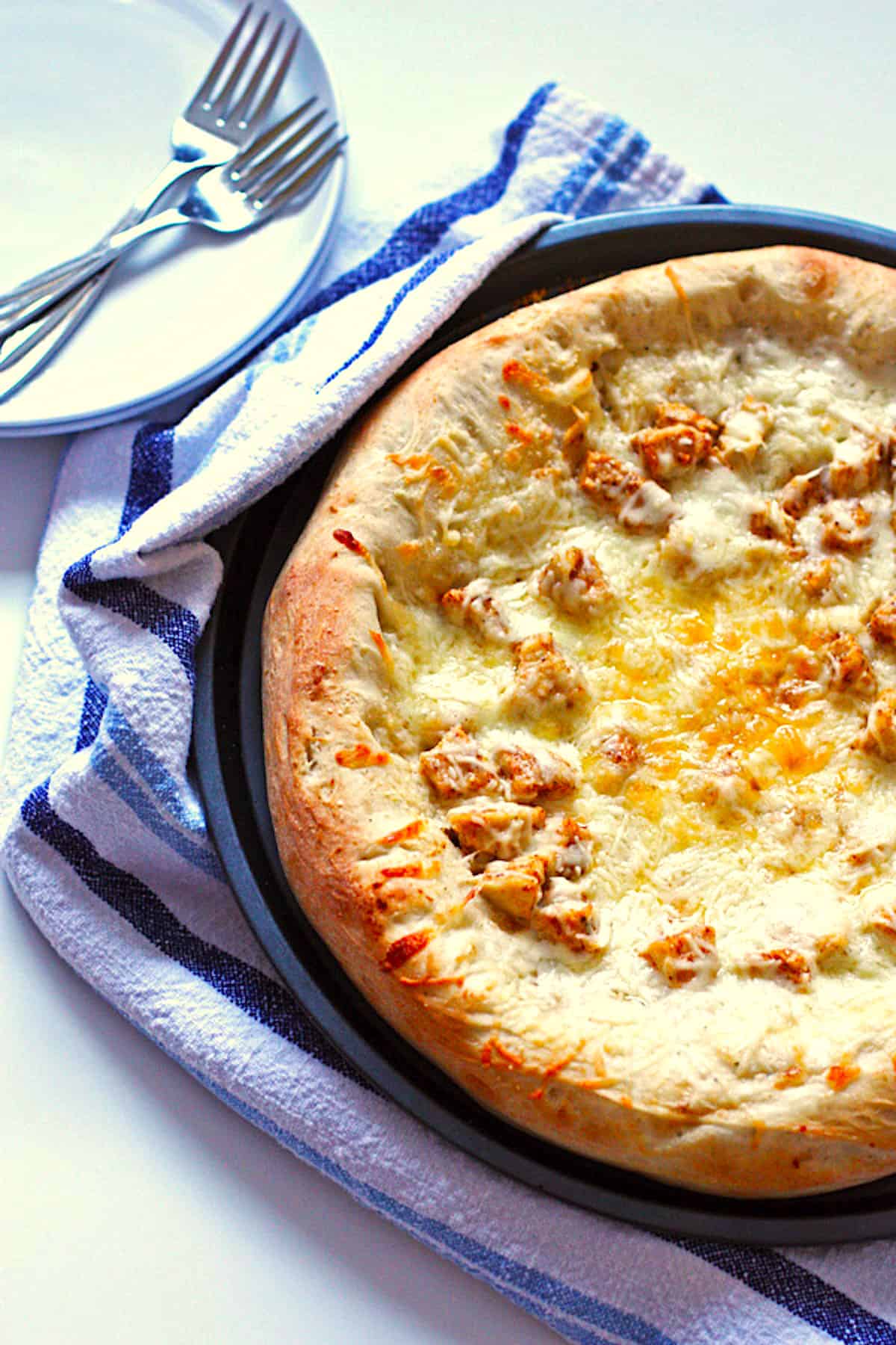 A homemade buffalo chicken wing pizza in a round pan with thick crust.