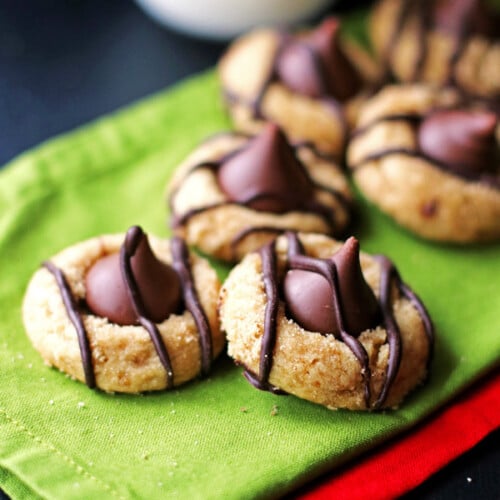Peanut Butter Kiss Cookies drizzled with melted chocolate sitting on green and red napkins.