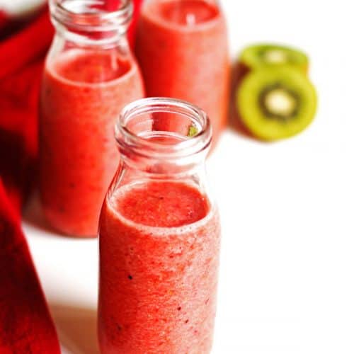 Smoothie in three glasses with sliced kiwi and a red napkin next the the glasses