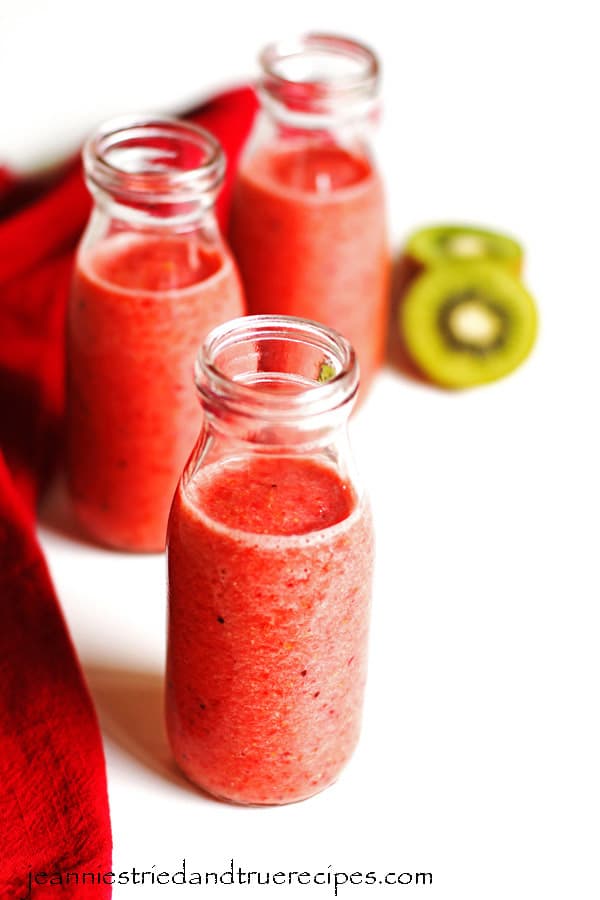 Smoothie in three glasses with sliced kiwi and a red napkin next the the glasses