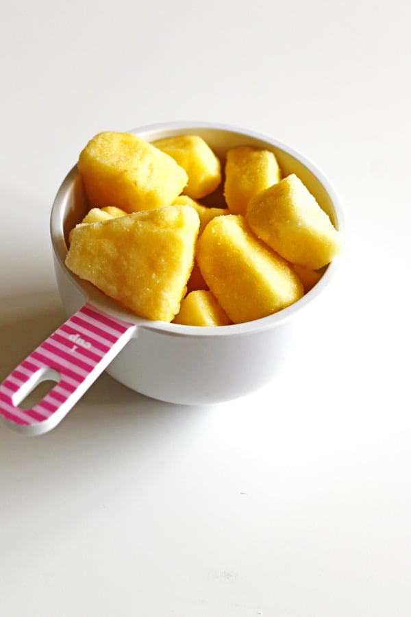 Frozen pineapple in a white measuring cup