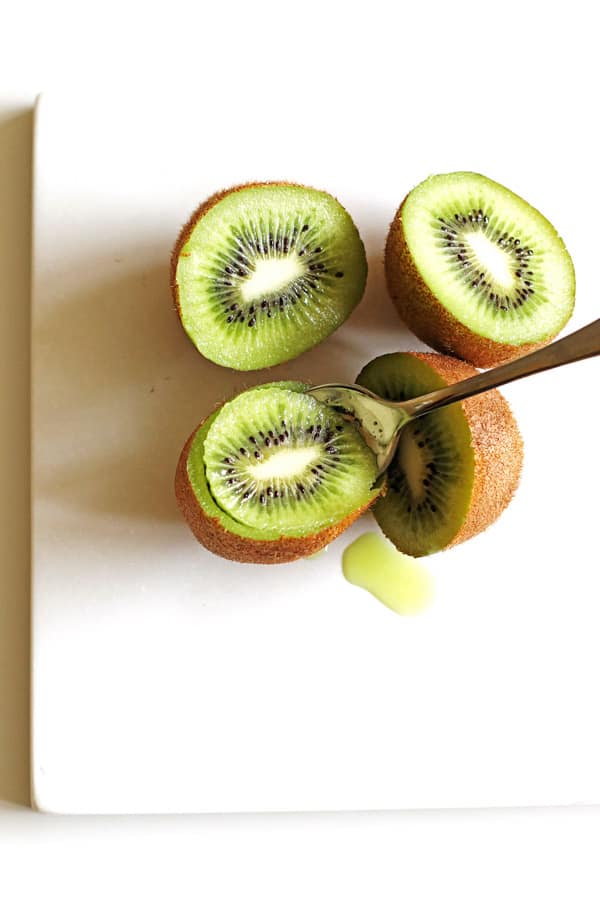 Scooping out the green kiwi using a spoon