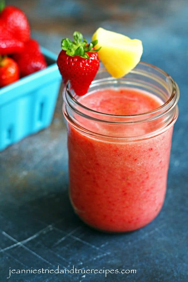 Strawberry Pineapple Smoothie in a glass with sliced strawberry and pineapple along the rim of the glass