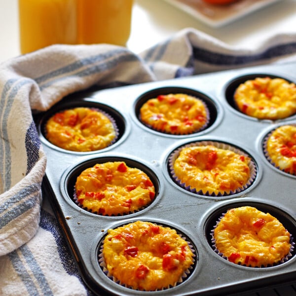 Egg Muffins in a muffin tin and glasses of orange juice in the background.