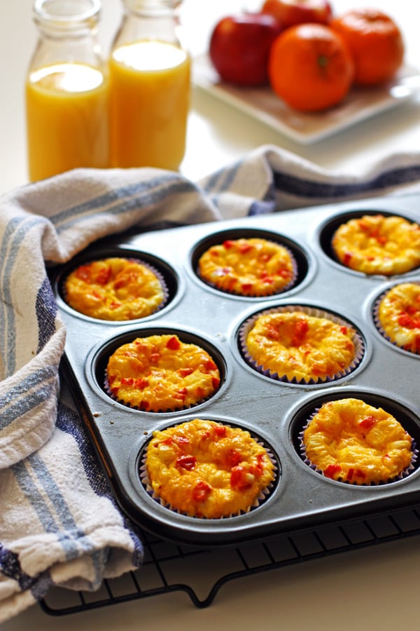 Egg Muffins in a muffin tin and glasses of orange juice in the background.