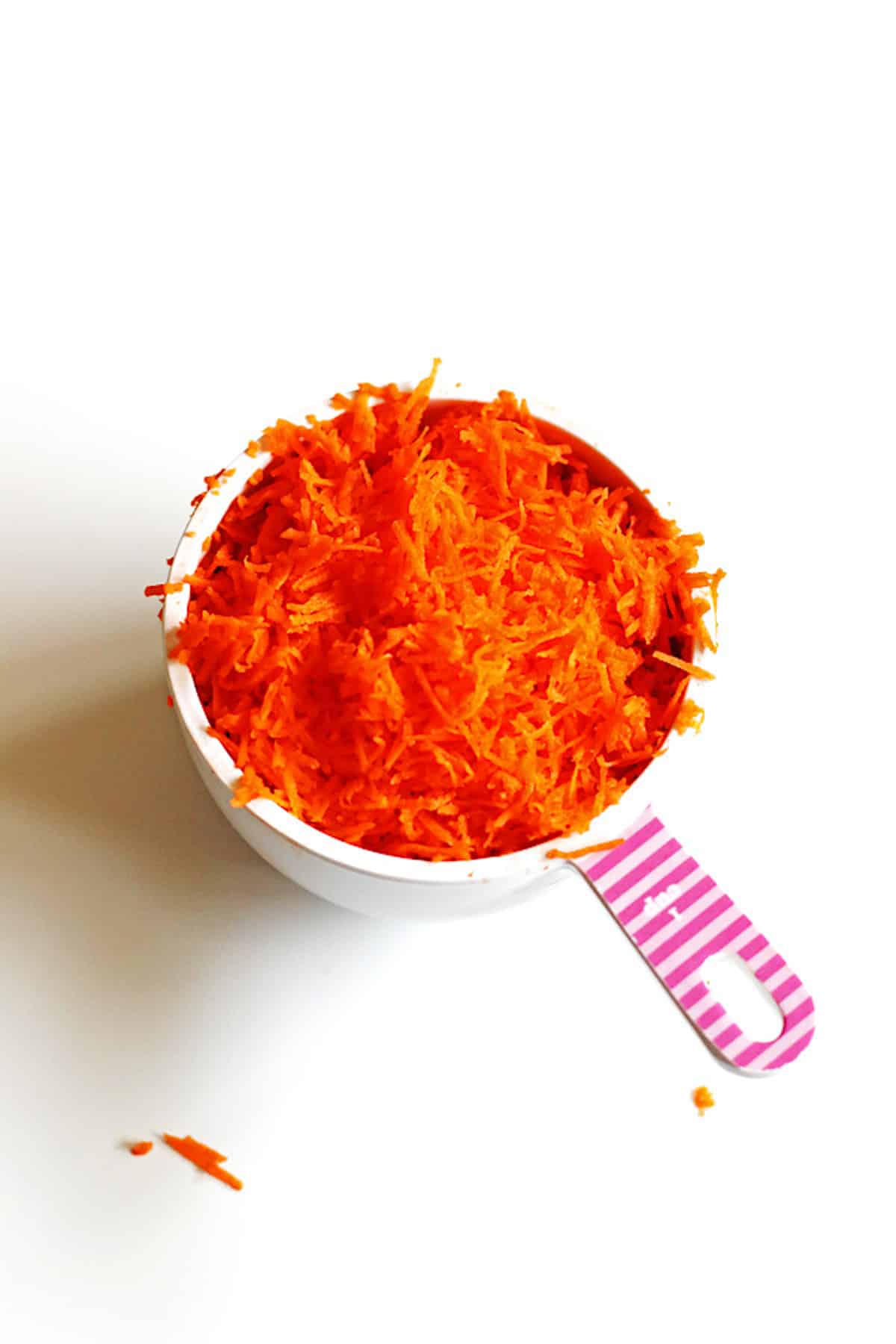 Shredded carrots in white and pink measuring cup