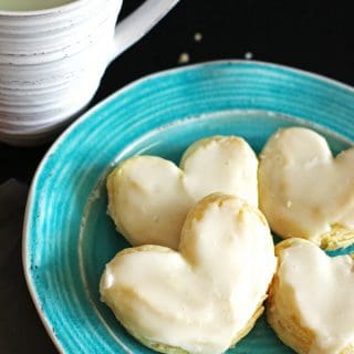 Frosted puff pastry hearts on a turquoise plate with a glass of milk
