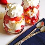 Layers of toasted angel food cake, fresh sliced strawberries and whipped cream in two clear glasses