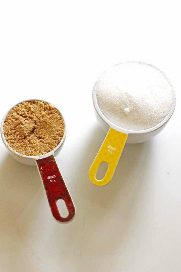 Brown sugar and granulated sugar measured out in measuring cups