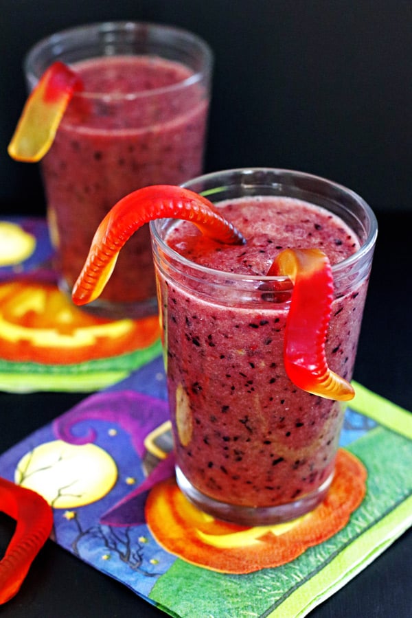 Purple smoothie in a glass with gummy worms and granola
