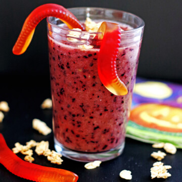 Purple smoothie in a glass with gummy worms and granola