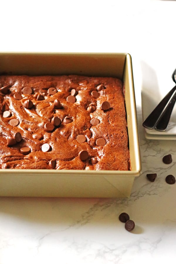 Brownies in a square baking pan with chocolate chips on top