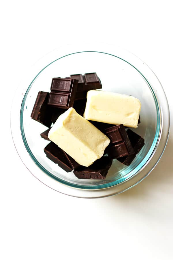 Butter and broken pieces of baker's chocolate in a clear bowl