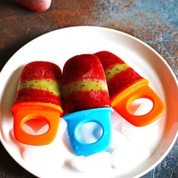 Strawberry Kiwi Popsicles on a white plate sitting on a multi-colored counter