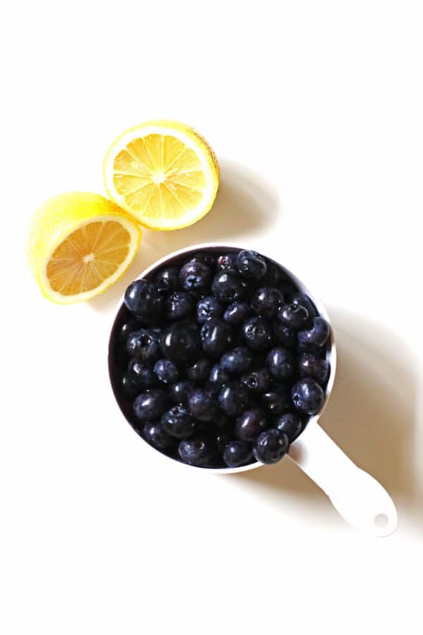 Lemon sliced in half and blueberries in a white measuring cup