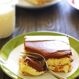 Slice of Eclair Cake on a white and green plate with a fork.