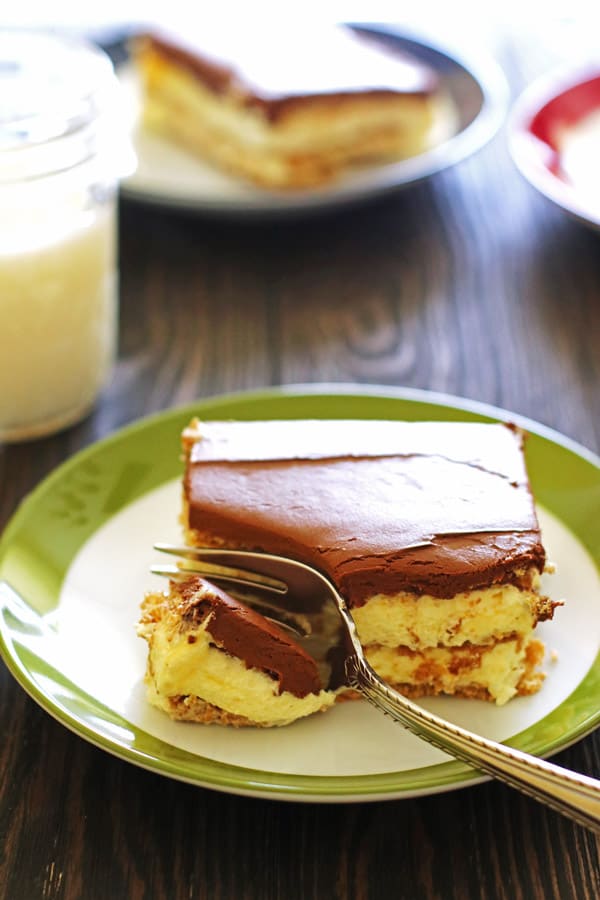 Slice of Eclair Cake on a white and green plate with a fork.