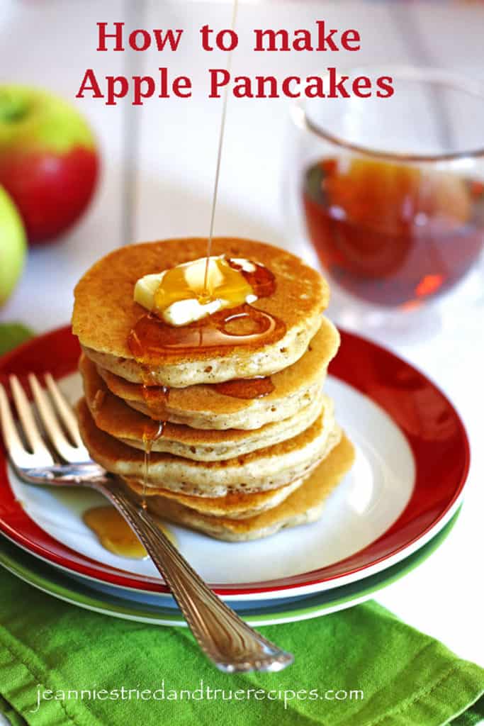 Ein Stapel Apfelpfannkuchen auf einem roten und weißen Teller. Es gibt eine Scheibe Butter auf den Pfannkuchen und Sirup wird über sie gegossen.