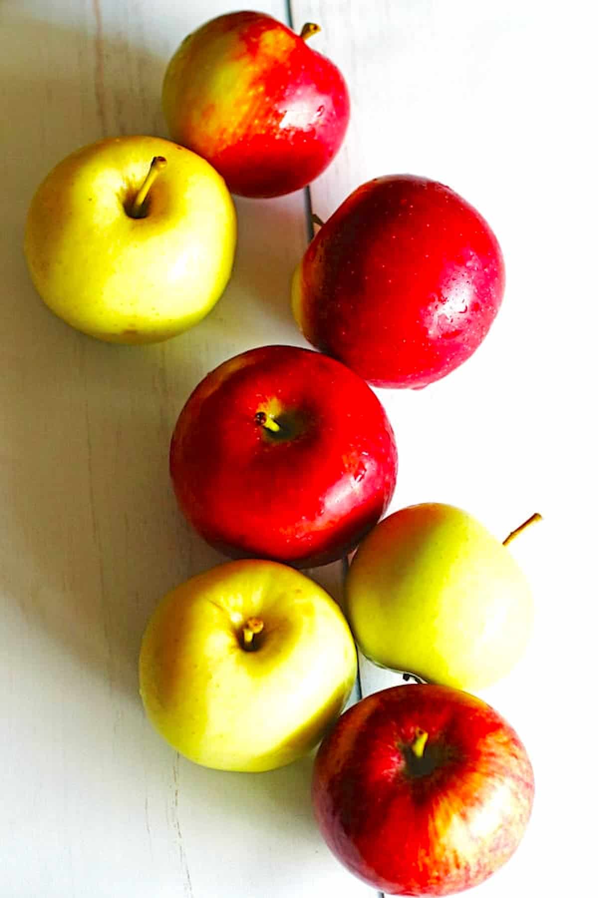 Red and green apples on a white table