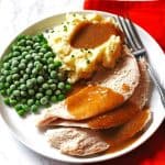 Turkey, mashed potatoes and peas on a white plate with a fork