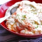 Mashed potatoes in a red bowl with a spoon