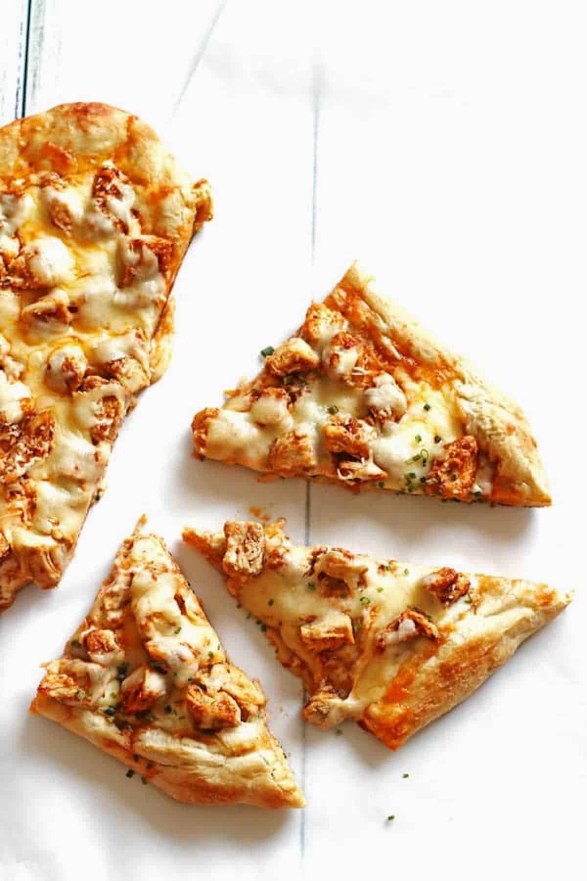 Pizza with chicken and cheese sliced on a white table
