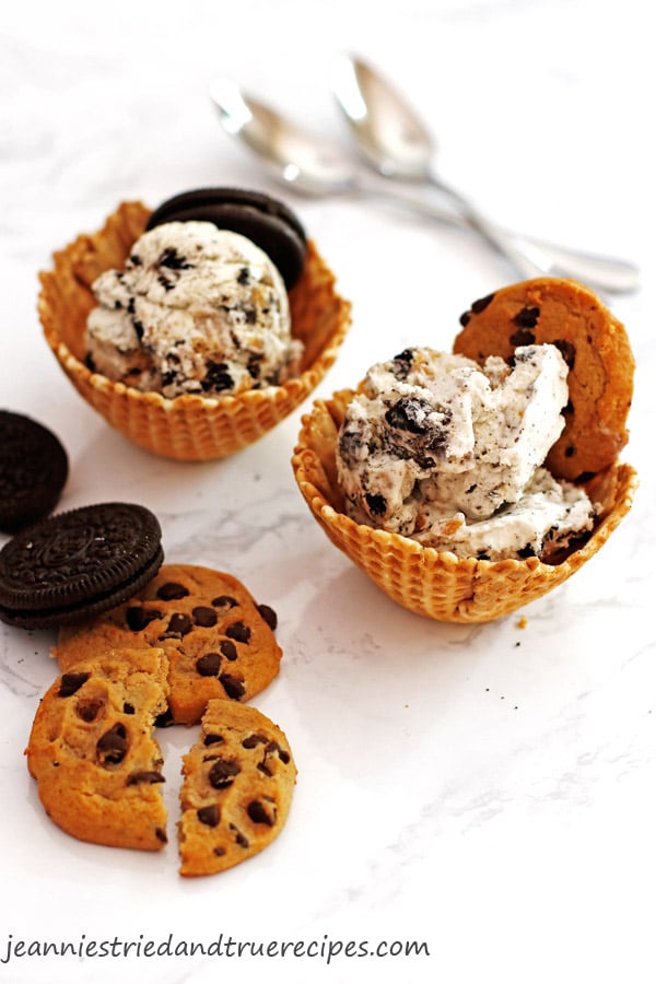 Cookies and cream ice cream placed in waffle cones and served with extra cookies on the side.
