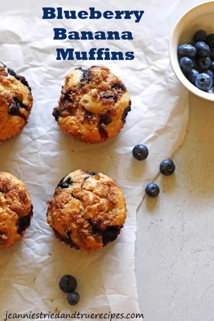 Muffins sur papier sulfurisé blanc avec un petit bol de myrtilles à côté