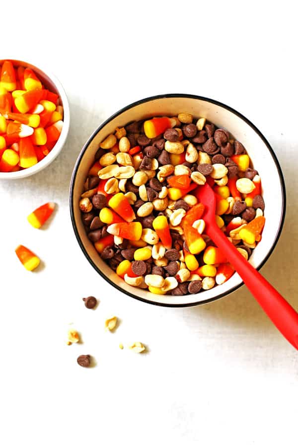 Mixing together the candy corn, chocolate chips and peanuts in a bowl with a large red spoon