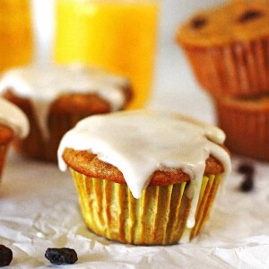 Carrot Cake Muffins on a white table with orange juice in a glass