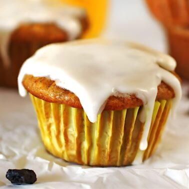 Carrot Cake Muffins on a white table with orange juice in a glass