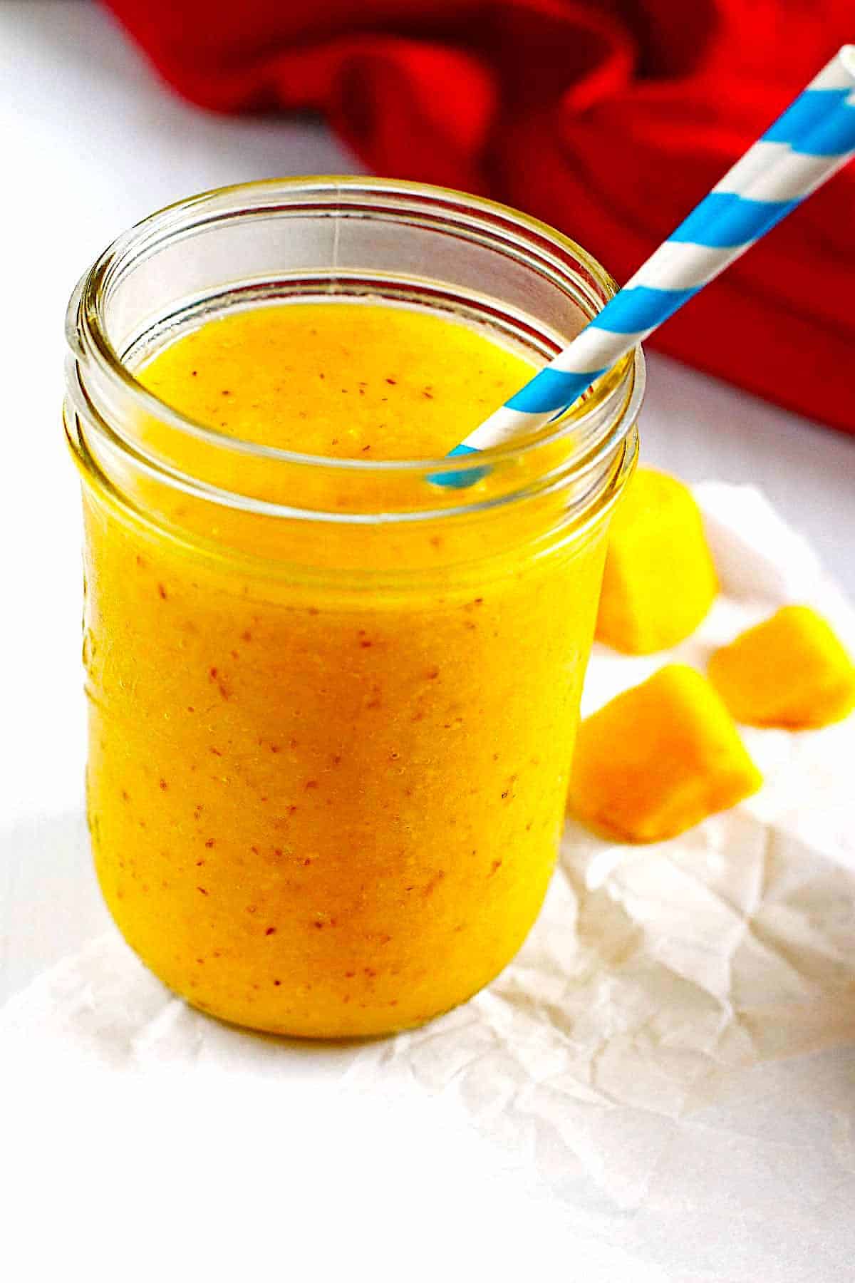Pineapple and Mango Smoothie in a canning jar with a straw.