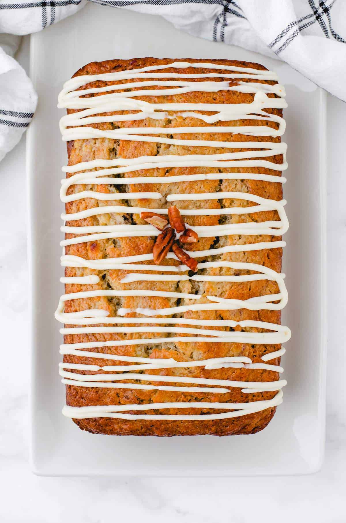 A loaf of buttermilk banana bread with Cream Cheese Frosting drizzled over the top.