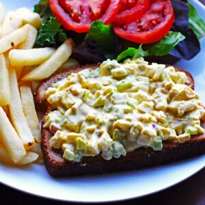 Egg salad with mustard, chopped celery, and onion on a slice of bread.