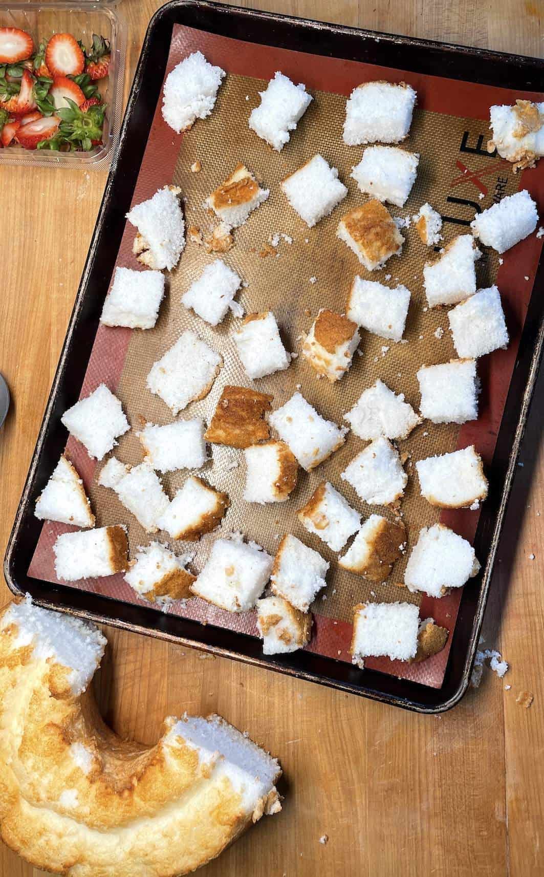 Angel food cake cut into cubes on a bake sheet before toasting to make shortcakes.
