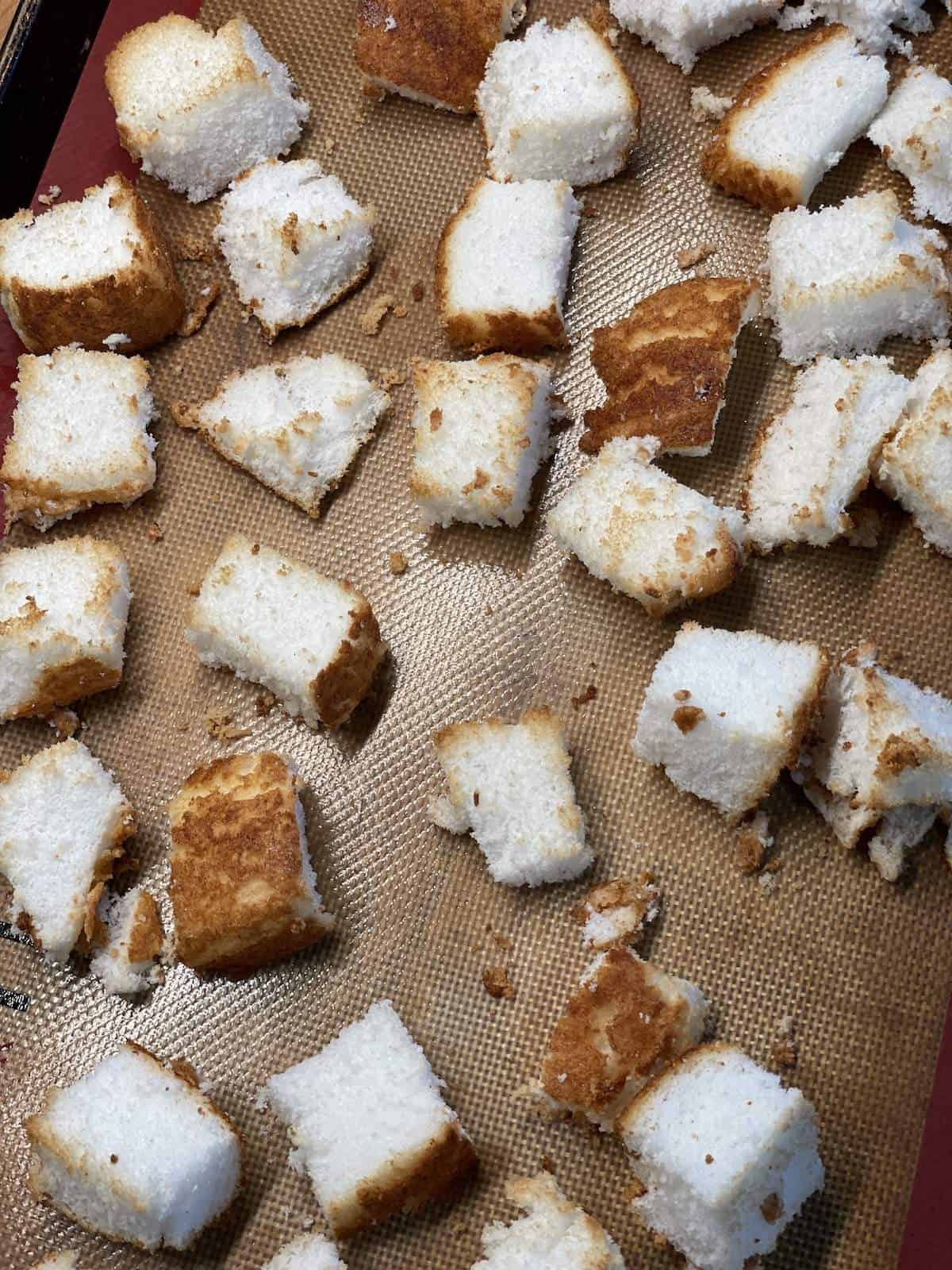 Toasted angel food cake cubes on a baking sheet.