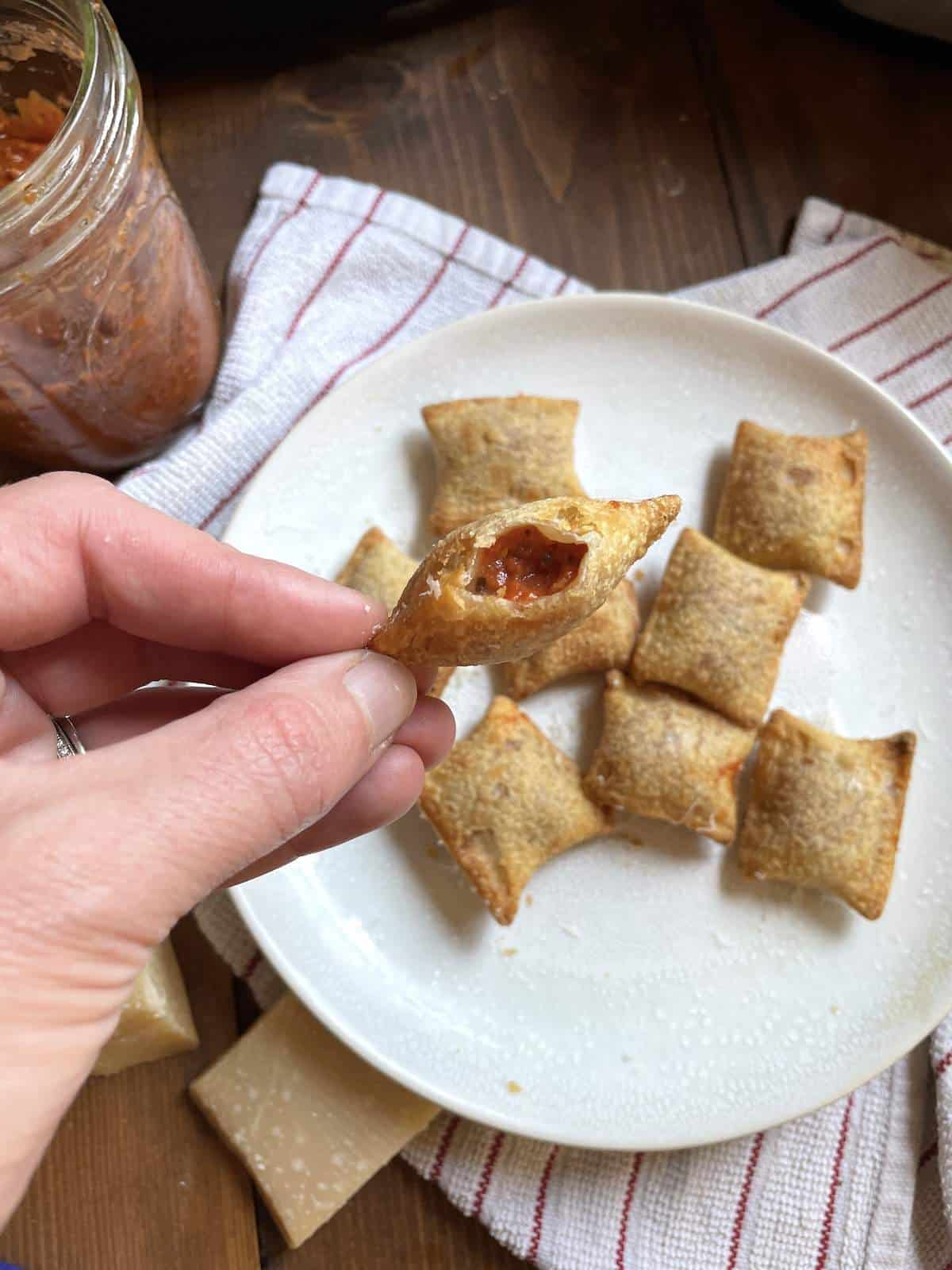 An air fried pizza roll bit open showing the inside over a plate of pizza bites.