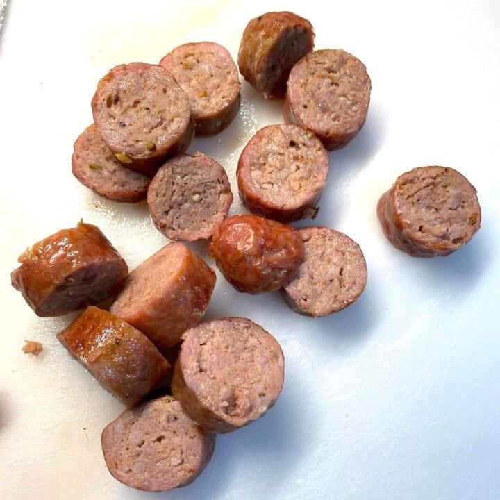 Oven-cooked, sliced Italian sausage on a white cutting board.