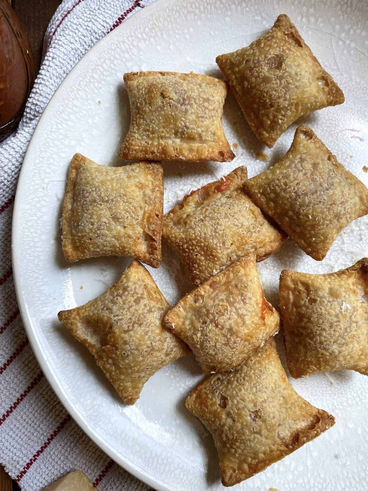 Air fried pizza rolls on a white plate.