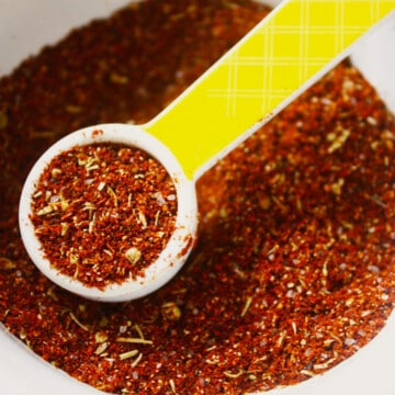 A bowl of mild taco seasoning in a small bowl with a yellow spoon.