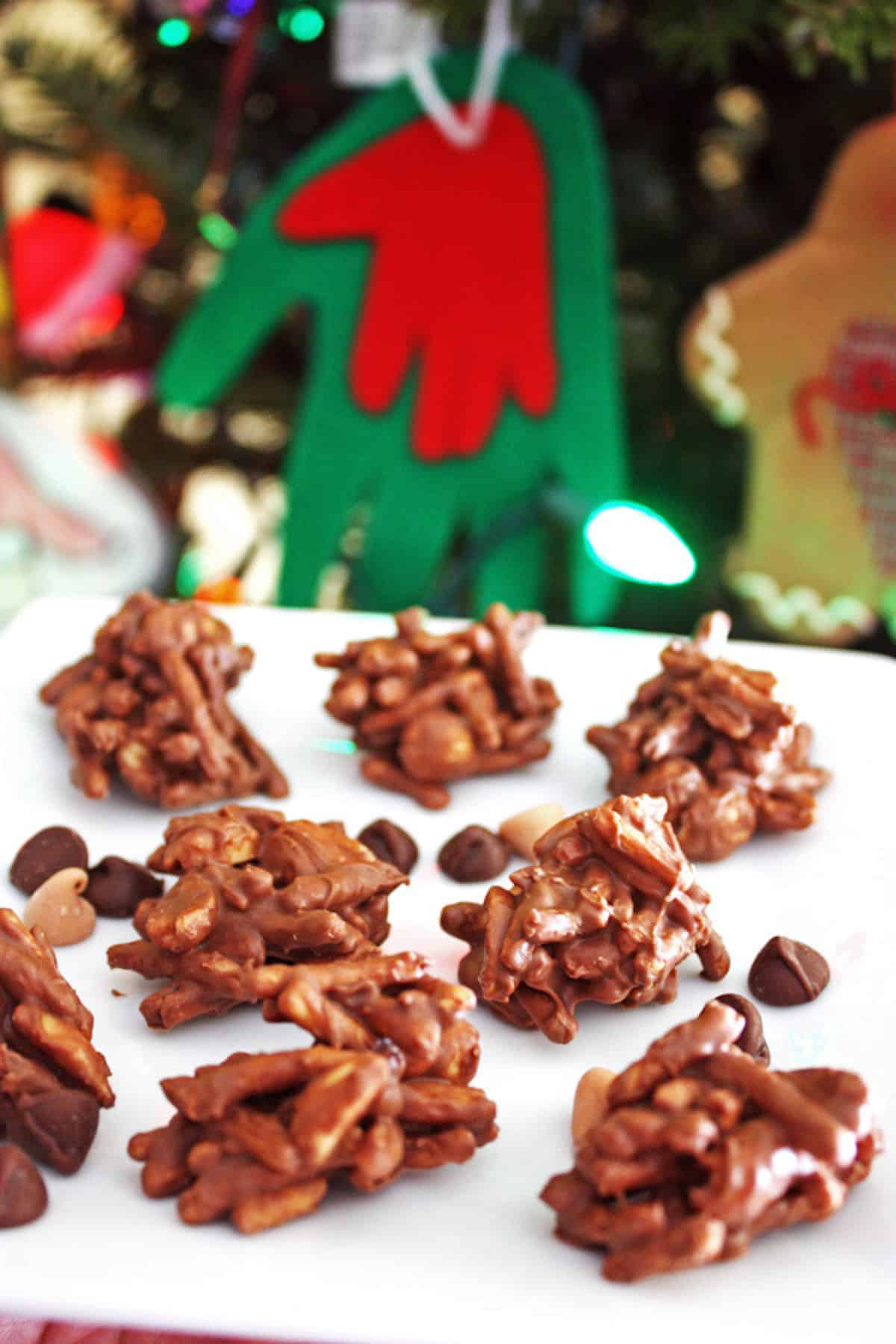 No bake haystack cookies on a white plate in front of a Christmas tree.